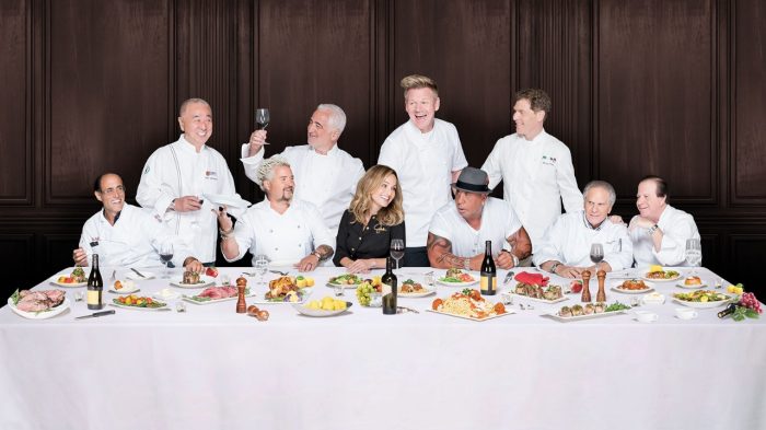 Group of celebrity chefs dining at a table.