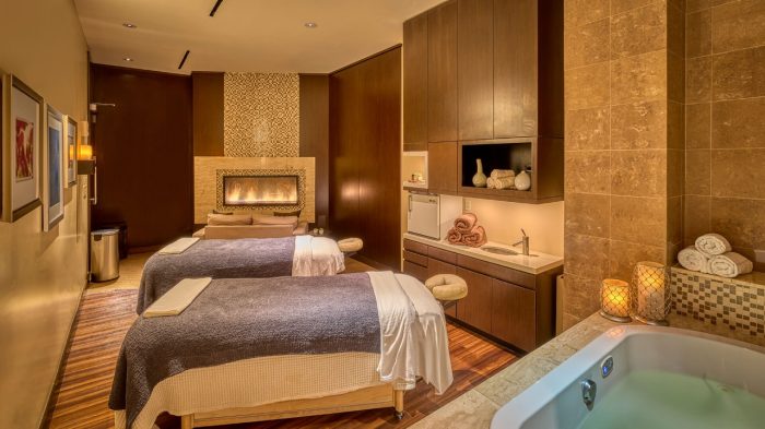 Side by side massage tables in room with a fireplace.