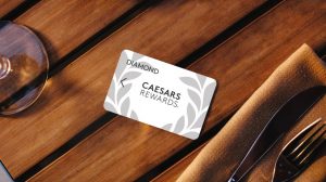 Diamond Caesars Rewards card on wooden table in between silverware and wine glass