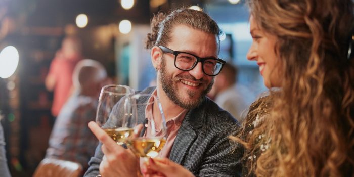 Two people toasting at a dinner table. Two people toasting at a dinner table.