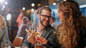 Two people toasting at a dinner table.