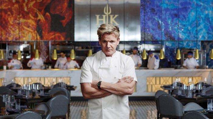 Gordon Ramsay in front of the red and blue kitchen of Hell's Kitchen