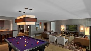 View Of Suite Showing A Pool Table, Living Room With Couches, Chairs And Coffee Table, Entertainment Center With Mounted TV, And Bar With Stools And View Into Bathroom Inside Nobu Hotel At Caesars Palace