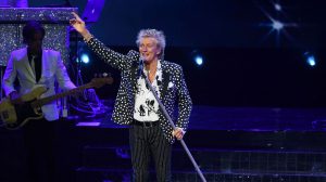 Rod Stewart holding his arm up while holding the microphone live at the Colosseum inside of Caesars Palace