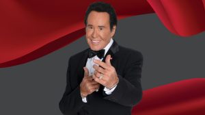 Wayne Newton in front of a red curtian