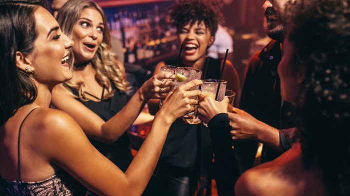 Group of friends laughing and toasting at a bar.
