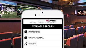 Image of Miomni sports betting app on phone and sports book in background