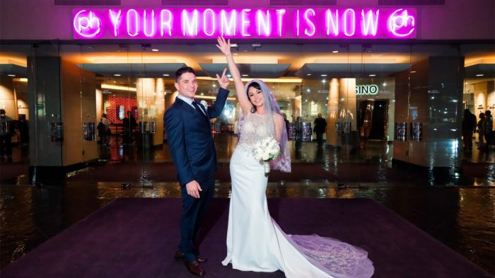 A couple standing in front of a sign that says Your Moment is Now