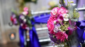 Close Up Of Wedding Chapel Chairs Wrapped In Purple Ribbon And Pink Flowers