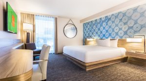 Photo Of King Suite Showing King Bed, Nightstand With Lamp, Mounted TV, Desk And Chair At The Linq Las Vegas