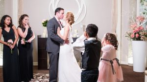 Photo Of Bride And Groom Sharing A Kiss With Wedding Party Standing By At The Chapel Inside The Flamingo Las Vegas