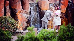 Photo Of Bride And Groom Taking A Photo In Front Of A Waterfall At The Flamingo Las Vegas