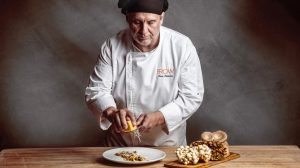 Chef grating Parmesan over dish.