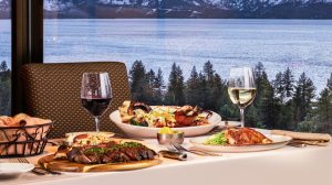 A table with plates of food and glasses of wine at Friday's Station overlooking Lake Tahoe.