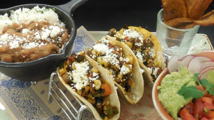 Three tacos with sides of beans and salsa at El Burro Borracho