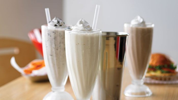 Variety of milkshakes with whip cream topping.