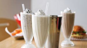 Variety of milkshakes with whip cream topping.