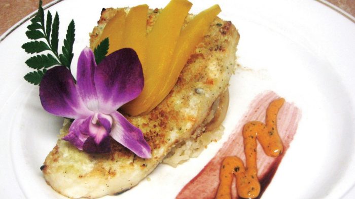 Fish filet on a plate, garnished with a flower.