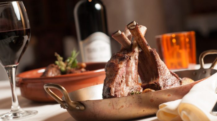 Dish with lamb chops and a glass of wine.