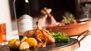 Chicken dish with side of potatoes and broccolini.