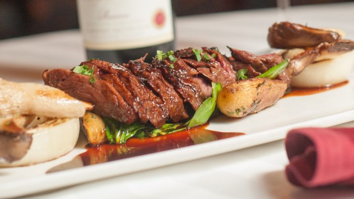 Sliced steak with potatoes and fresh garnish.