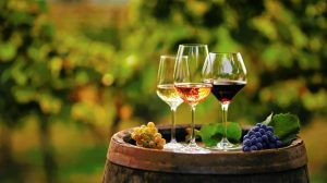 Three glasses of wine on top of a wine barrel.