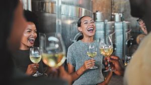 Group of friends at a wine tasting surrounded by steel barrels.