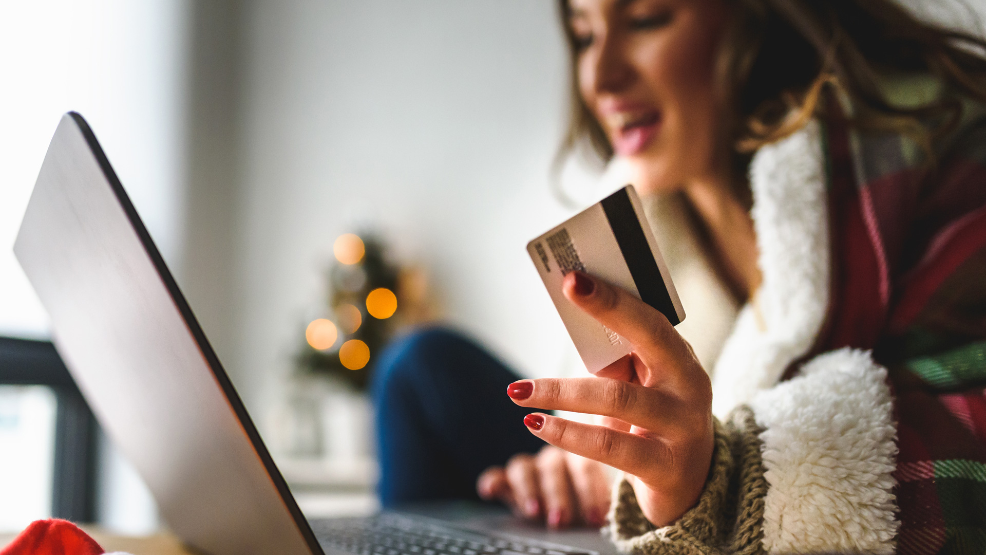 Women holding a gift card in her hand while shopping online.