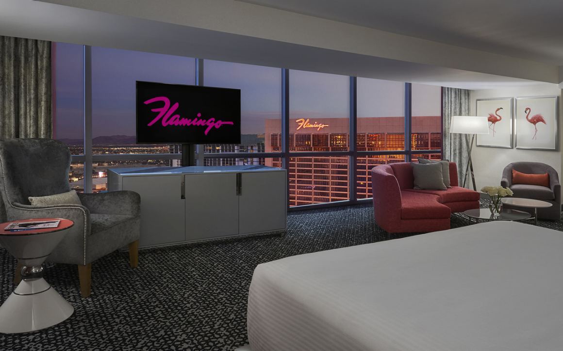 Hotel room with modern decor, large windows, and a view of a cityscape.