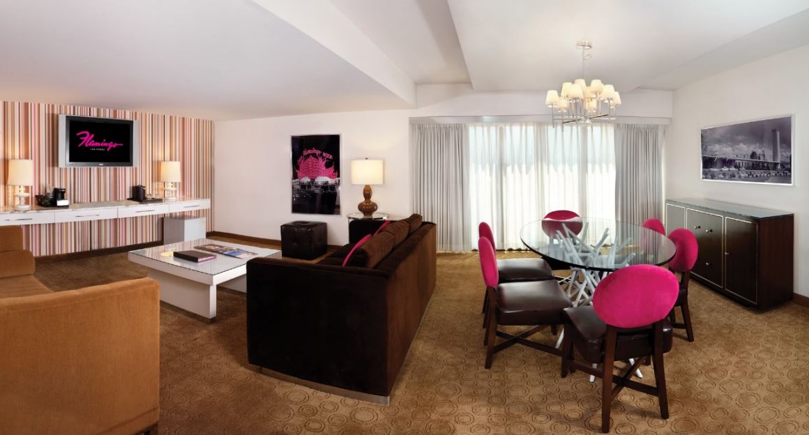 Spacious hotel room with a seating area, dining table, and modern decor.