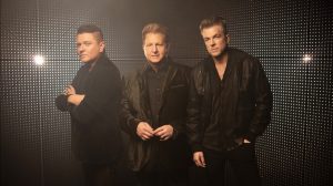 Rascal Flatts in front of a black and dotted background.