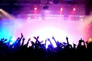 Crowd At A Concert With Hands In The Air And Bright Lights Coming From Stage