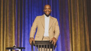 Ali Siddiq in front of a blue and yellow curtain.