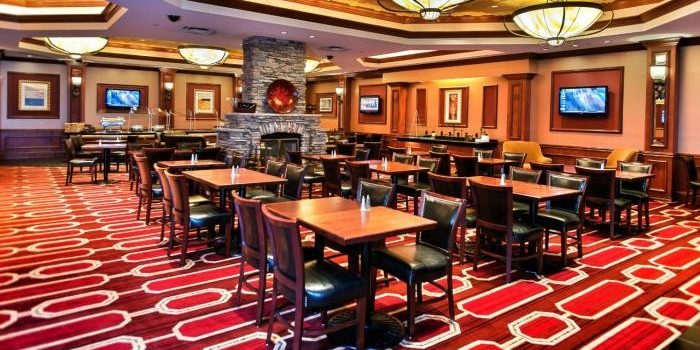 View Inside General Managers Club Showing Dining Tables With Chairs, Fire Place, And TV's Mounted On The Walls At The Horseshoe Council Bluffs