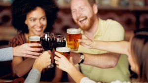 Group of friends toasting beer and wine glasses.