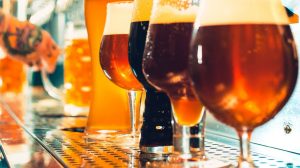 Row of beer glasses being poured from tap.