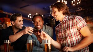 Three men toasting shot glasses.