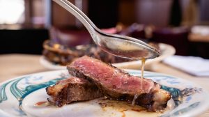 Plated steak slices with gravy being poured on them