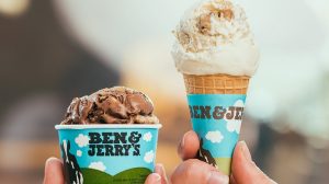 Hands holding up an ice cream cone and a cup of ice cream.