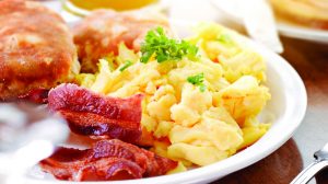 Plate of scrambled eggs, bacon and biscuits with parsley