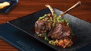 Lamb chops plated and garnished with fresh parsley sprigs.