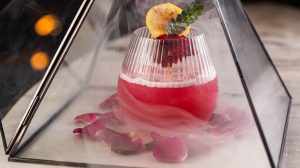 Louvre at First Sight, a decadent mezcal & prickly pear cocktail smoked with hickory and delivered in a mini version of the large pyramid at the Louvre museum in Paris at Vanderpump à Paris, Paris Las Vegas