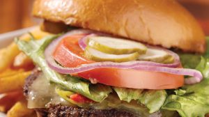 Hamburger with fresh vegetables and side of fries.